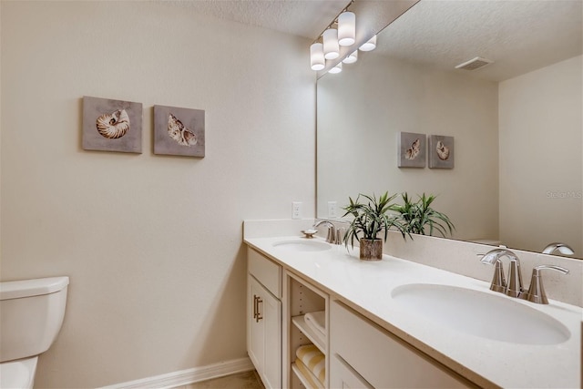 bathroom featuring a textured ceiling, vanity, and toilet