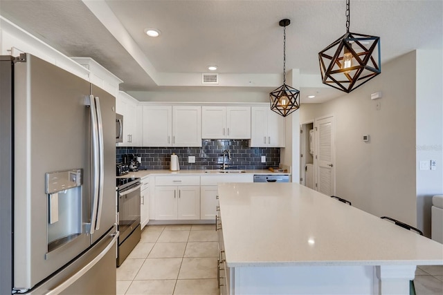 kitchen with sink, white cabinets, light tile patterned flooring, pendant lighting, and appliances with stainless steel finishes