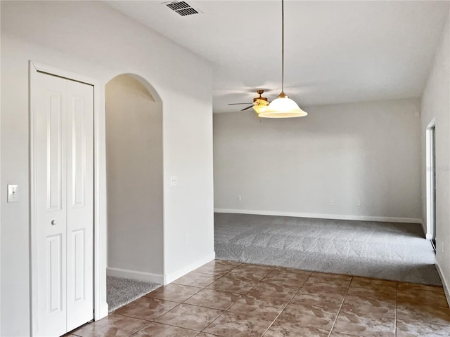 carpeted spare room featuring ceiling fan