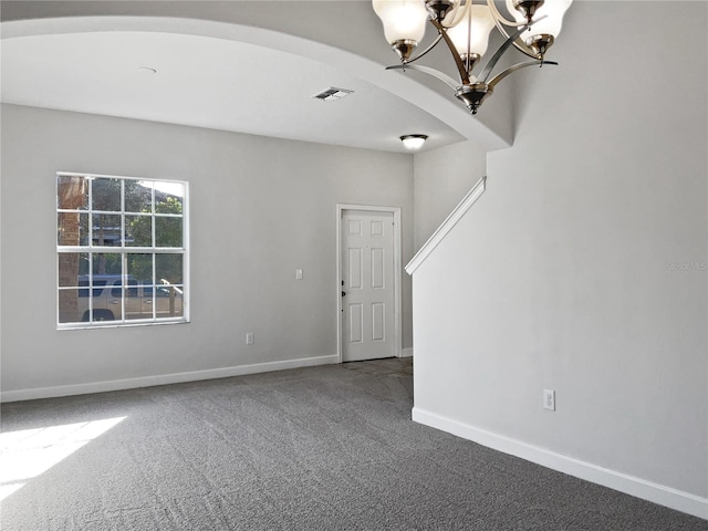 unfurnished room with carpet floors and a chandelier