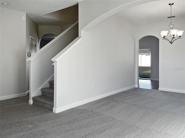 carpeted empty room featuring a notable chandelier