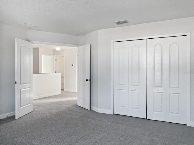 unfurnished bedroom with a textured ceiling, a closet, and carpet