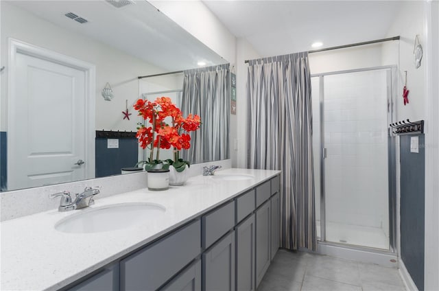 bathroom with a shower with door, vanity, and tile patterned floors