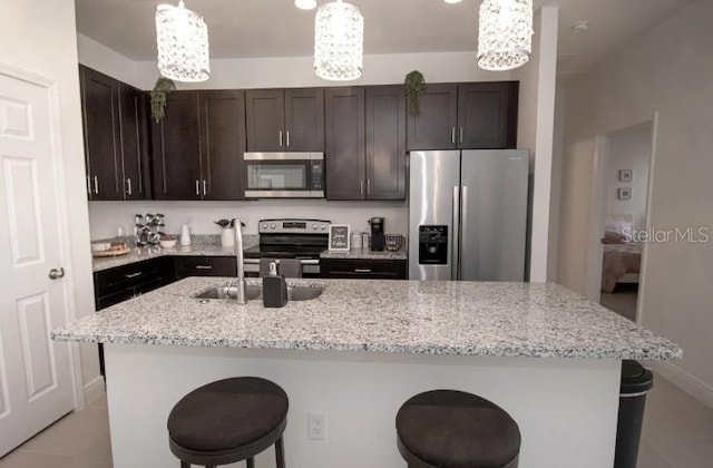 3179 W Barberton Pl, Citrus Springs, FL 34433 - kitchen featuring stainless steel appliances, a kitchen bar, dark brown cabinets, a center island with sink, and light stone countertops
