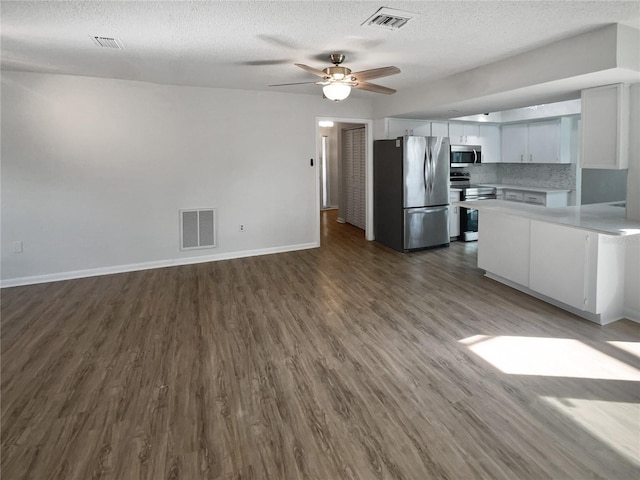 kitchen featuring stainless steel appliances, dark hardwood / wood-style flooring, a textured ceiling, white cabinetry, and tasteful backsplash