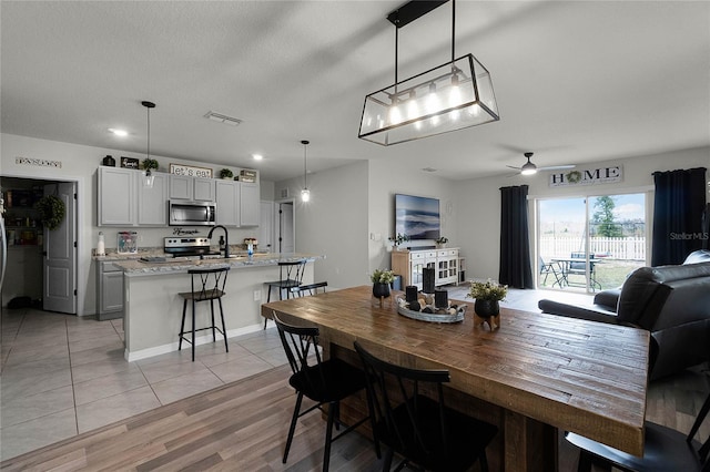 tiled dining room featuring ceiling fan and sink