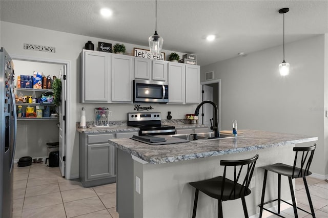 kitchen with sink, stainless steel appliances, a kitchen island with sink, and pendant lighting