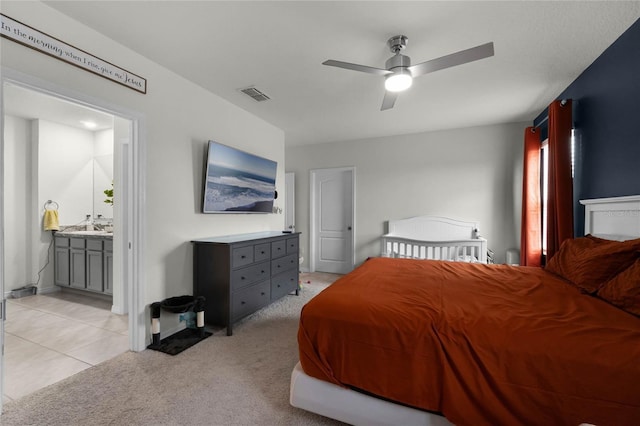 bedroom featuring sink, ensuite bath, light carpet, and ceiling fan