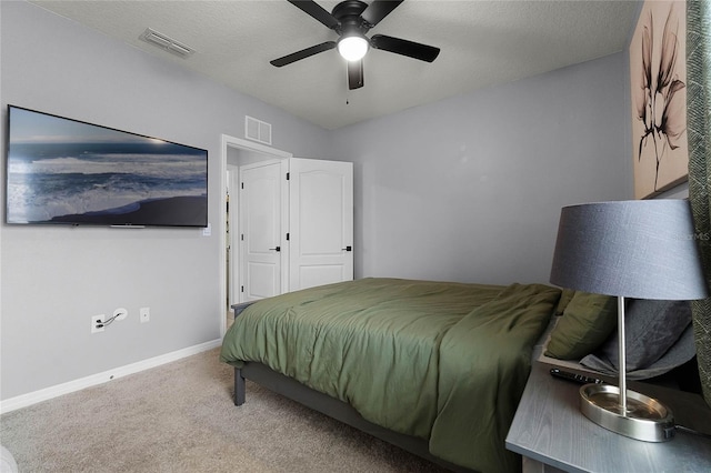 bedroom with ceiling fan, carpet floors, and a textured ceiling