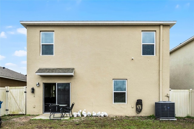 back of property with central AC unit and a patio