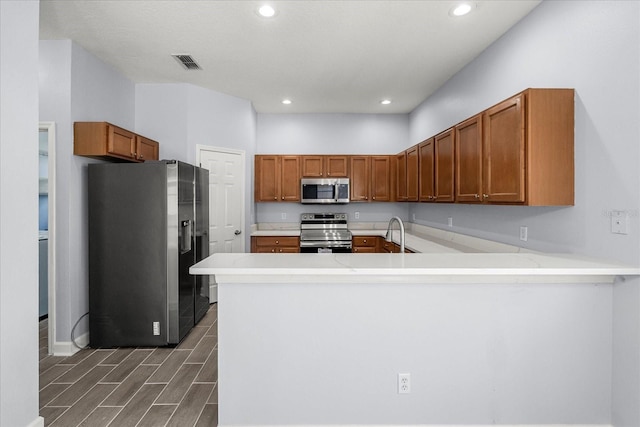 kitchen featuring kitchen peninsula, stainless steel appliances, and sink