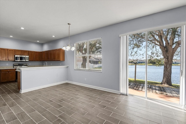 kitchen with kitchen peninsula, a chandelier, decorative light fixtures, stainless steel appliances, and a water view