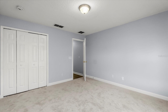 unfurnished bedroom with a closet and light carpet