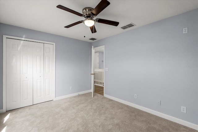 unfurnished bedroom featuring ceiling fan, a closet, and carpet flooring