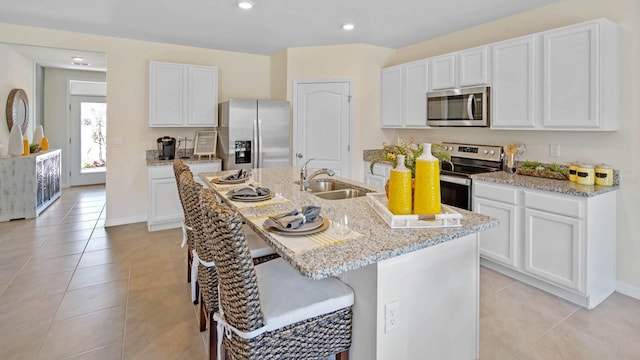 kitchen featuring white cabinets, a center island with sink, stainless steel appliances, light tile patterned floors, and sink