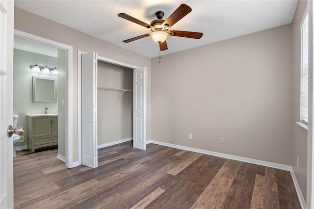 unfurnished bedroom featuring ceiling fan, ensuite bath, a textured ceiling, and hardwood / wood-style flooring