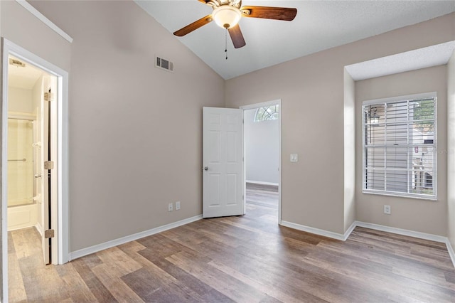 unfurnished bedroom featuring ensuite bath, ceiling fan, vaulted ceiling, and light hardwood / wood-style flooring