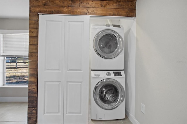 laundry area with stacked washing maching and dryer and light tile patterned floors