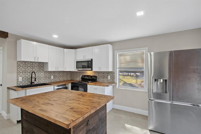 kitchen with stainless steel appliances, light tile patterned floors, wood counters, white cabinetry, and sink