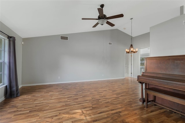 living room with lofted ceiling, dark wood-type flooring, and ceiling fan with notable chandelier