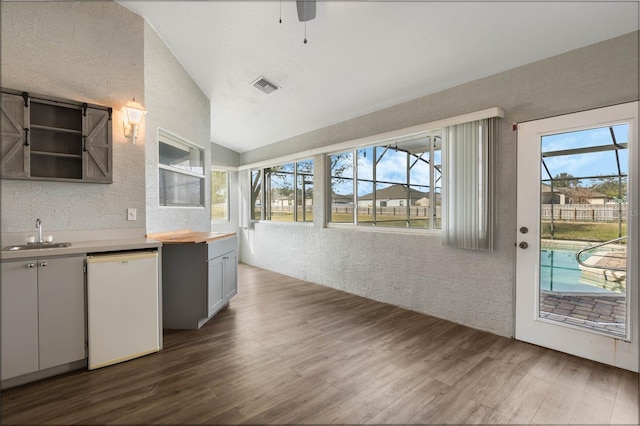 kitchen with dark wood-type flooring, ceiling fan, sink, vaulted ceiling, and white dishwasher