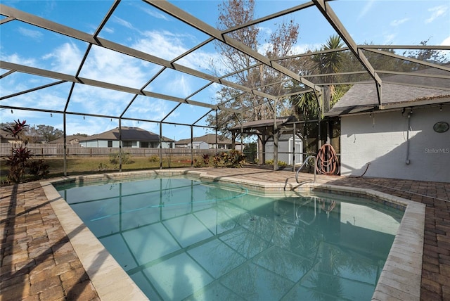 view of pool with glass enclosure, a patio area, and a shed