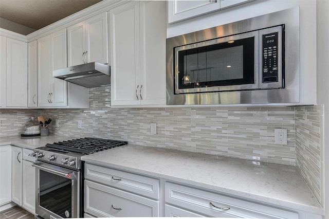 kitchen with white cabinets, decorative backsplash, light stone countertops, and stainless steel appliances