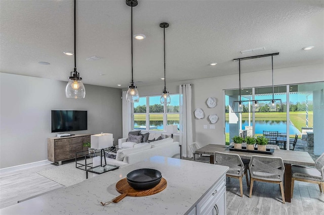 living room featuring a textured ceiling, a water view, and light wood-type flooring