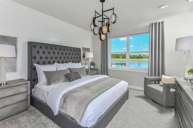 carpeted bedroom featuring a textured ceiling and a water view