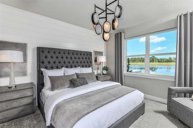 carpeted bedroom with a water view and a textured ceiling