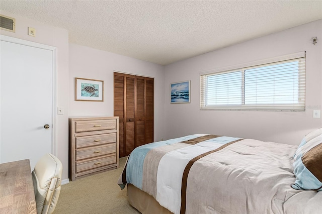 bedroom featuring a textured ceiling, a closet, and light colored carpet