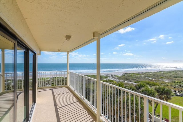 balcony with a water view and a view of the beach