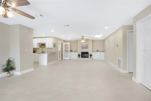 unfurnished living room featuring sink, a skylight, and ceiling fan