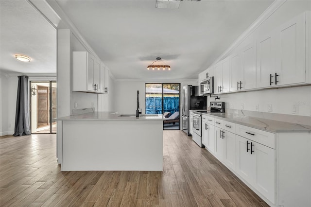 kitchen featuring white cabinets, appliances with stainless steel finishes, ornamental molding, and kitchen peninsula