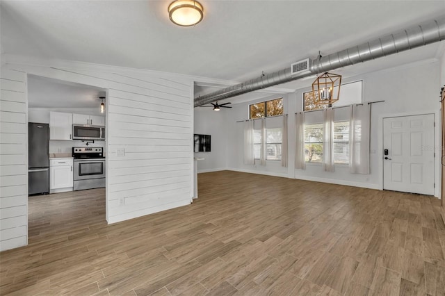 unfurnished living room with ceiling fan, a barn door, and light wood-type flooring