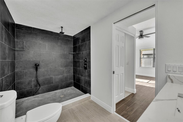 bathroom featuring ceiling fan, toilet, and tiled shower