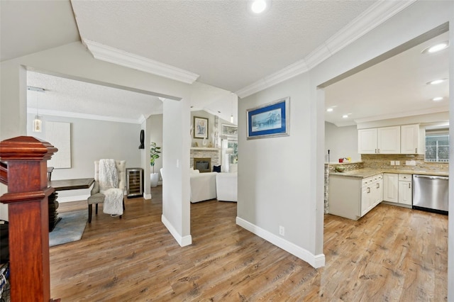 kitchen with white cabinetry, decorative backsplash, light wood-type flooring, dishwasher, and a textured ceiling