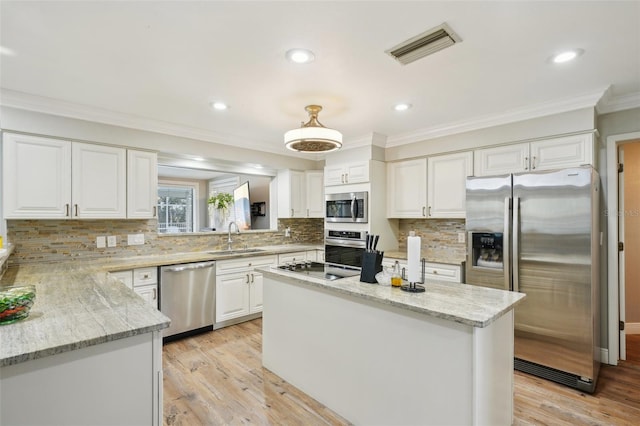 kitchen with stainless steel appliances, sink, white cabinets, and light stone countertops