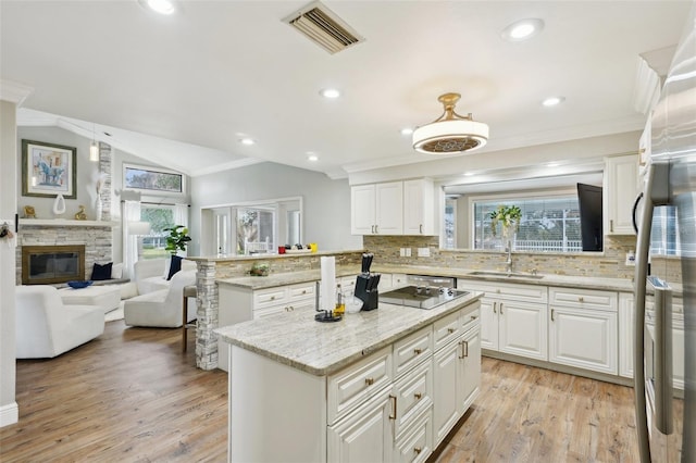 kitchen featuring vaulted ceiling, a kitchen island, white cabinetry, and sink