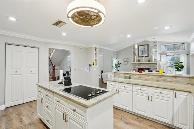 kitchen with white cabinetry, light hardwood / wood-style floors, black electric cooktop, light stone countertops, and a kitchen island