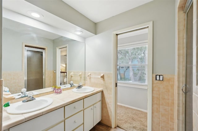 bathroom with vanity, tile walls, and a shower with door