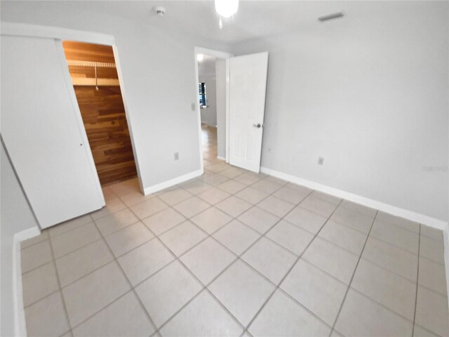 unfurnished bedroom featuring a spacious closet, a closet, and light tile patterned flooring