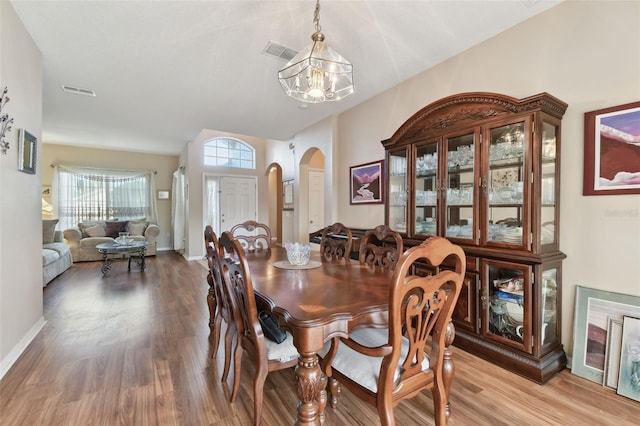 dining room featuring wood finished floors, visible vents, baseboards, arched walkways, and a notable chandelier