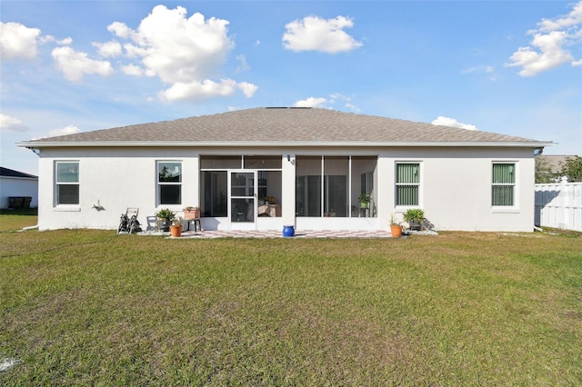 back of house with fence, roof with shingles, a yard, a sunroom, and stucco siding