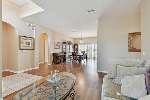 living room with visible vents, arched walkways, baseboards, and wood finished floors