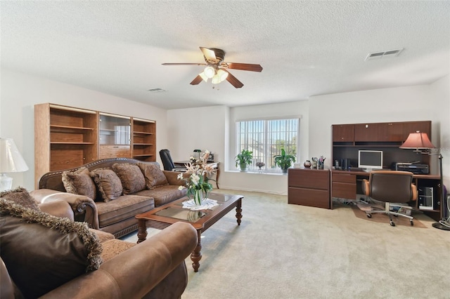 living area with visible vents, light carpet, a textured ceiling, and a ceiling fan