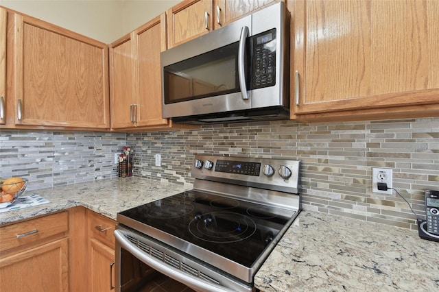 kitchen featuring light stone countertops, tasteful backsplash, and appliances with stainless steel finishes