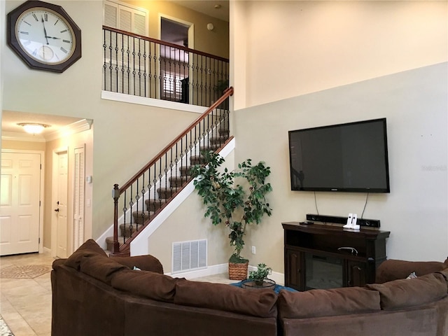 living room with crown molding, a towering ceiling, and light tile patterned floors