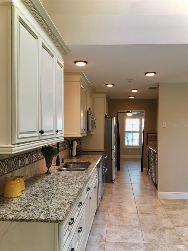 kitchen with sink, white cabinetry, light stone countertops, and stainless steel appliances