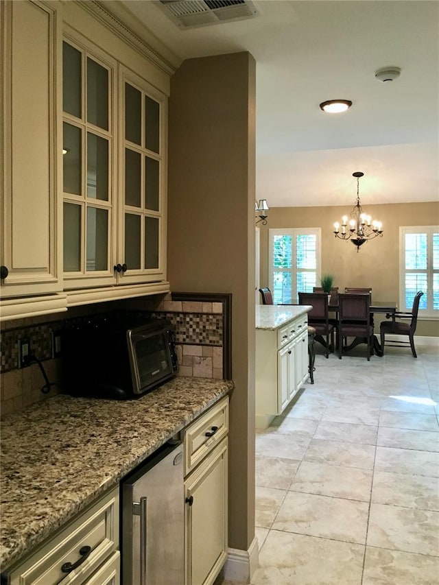 kitchen featuring cream cabinetry, pendant lighting, light tile patterned floors, and plenty of natural light